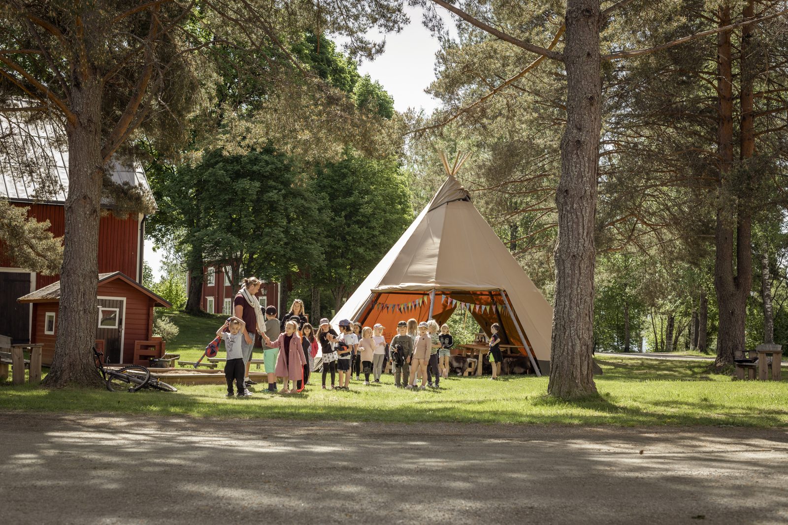 Children and their teacher gathered outside an outdoor tipi classroom