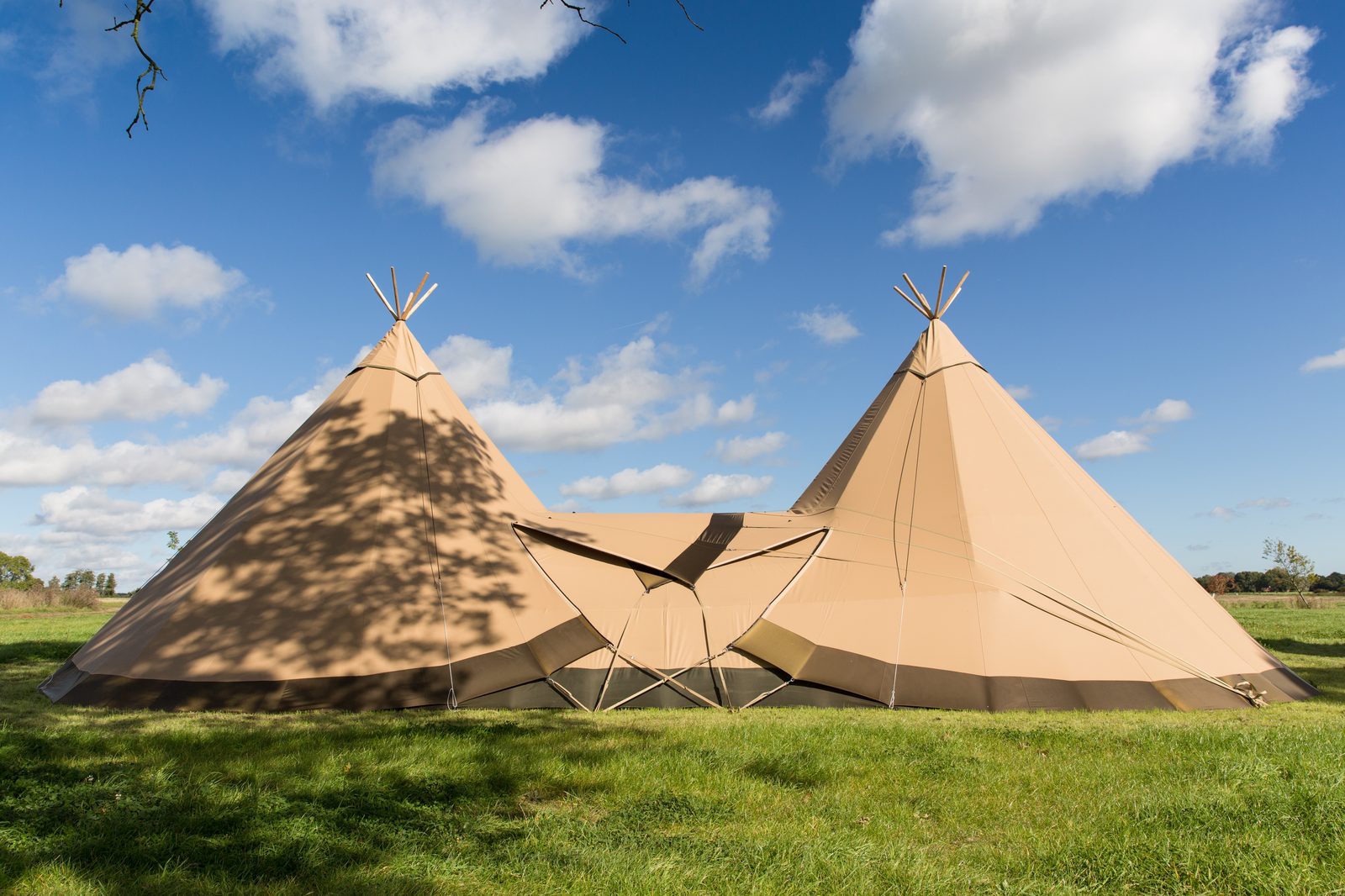 Two large Beehive tipis linked together in a meadow under a clear blue sky — outdoor classroom service across the UK