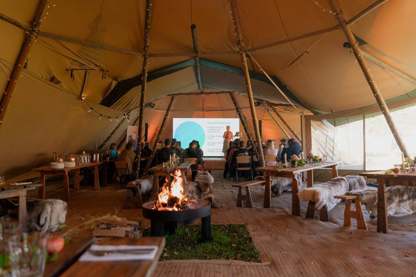 People watching presentation inside linked tipis, demonstrating professional outdoor learning space capacity for independent schools