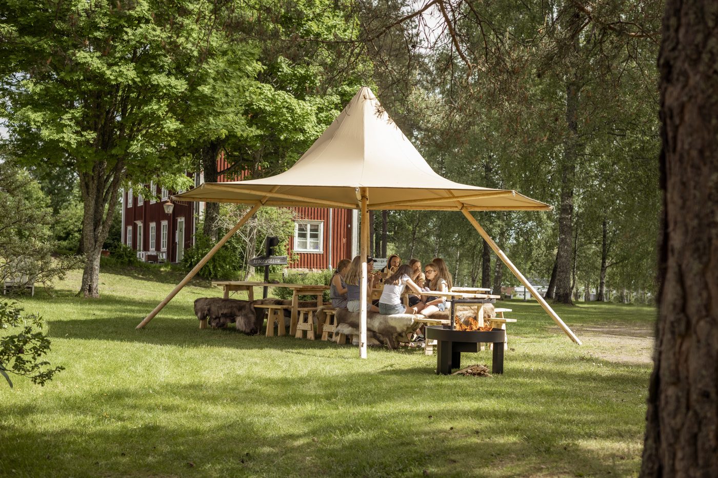Adults and children enjoying outdoor activities at the forest school shelter showing year-round learning environment