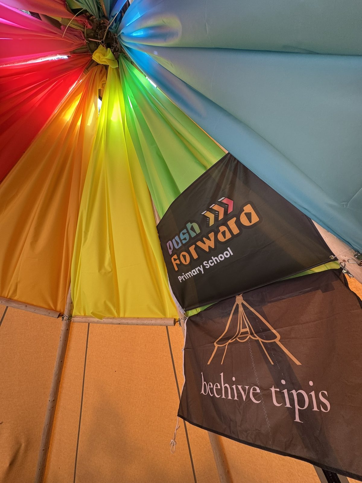 The Push Forward Primary School and Beehive Tipis banners hanging beneath the rainbow canopy