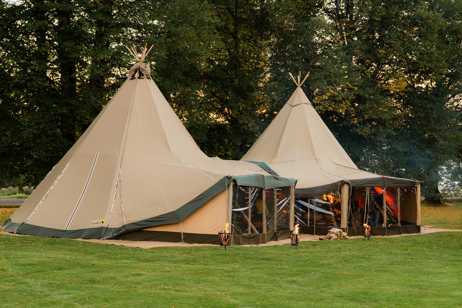 Two Beehive Stratus 72 tipis linked together at dusk in a parkland setting — South East prep schools
